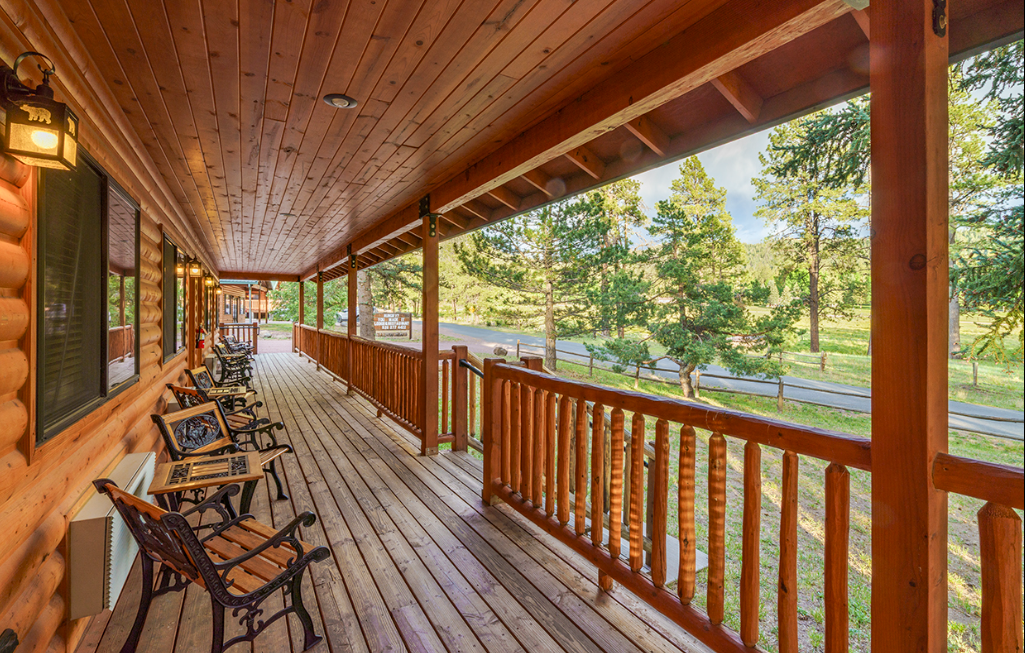 Chairs line a covered wooden porch overlooking pine trees at Long Shadow Lodge near Alpine, Arizona.